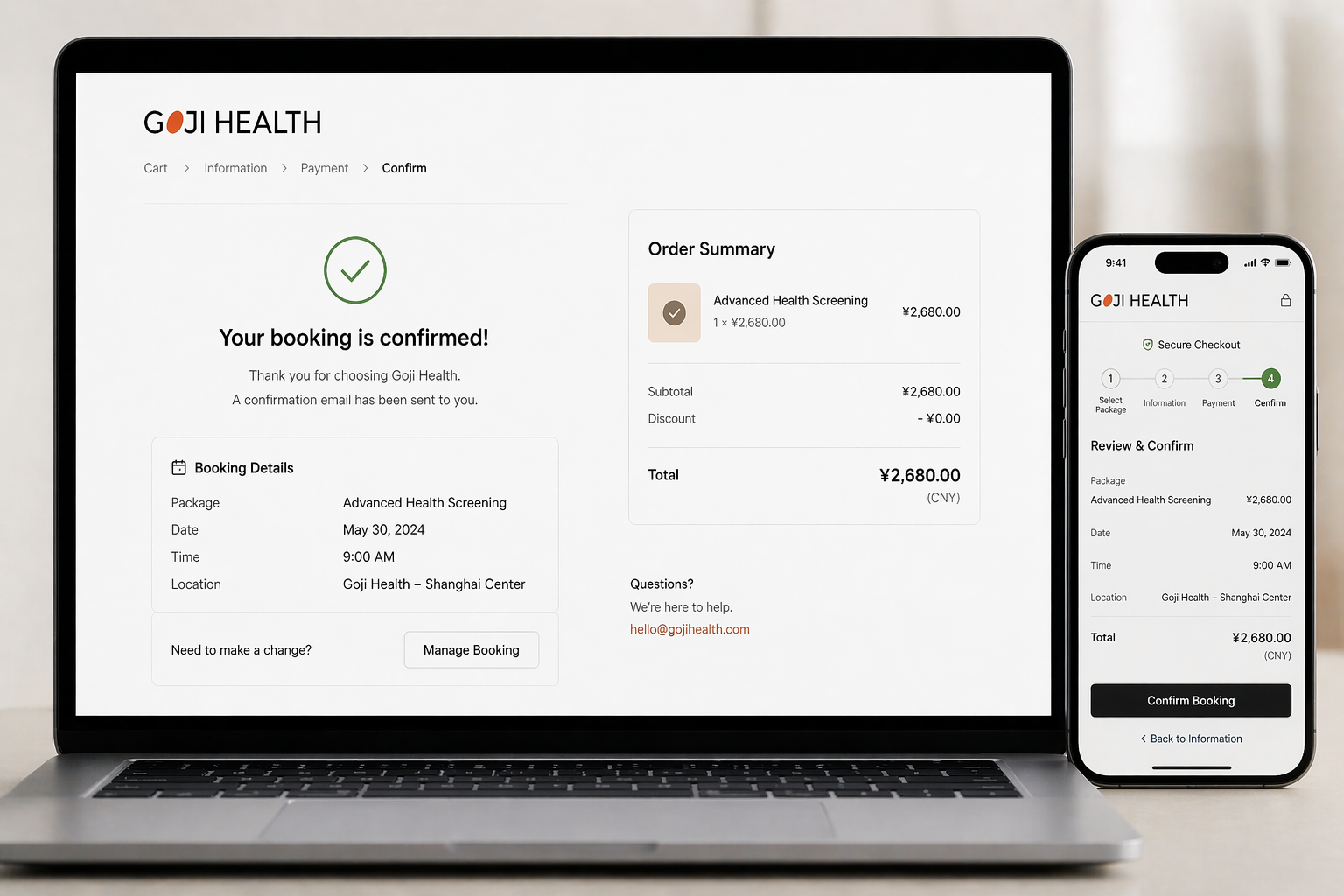 Laptop and smartphone displaying Goji Health booking confirmation on a light background